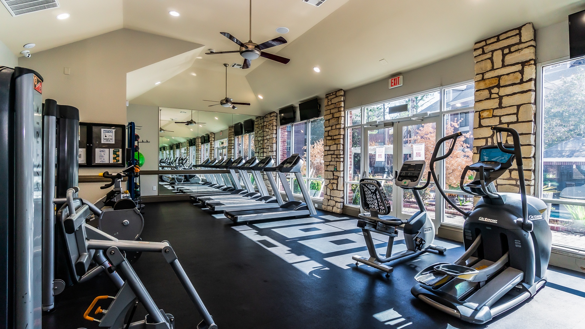 A gym with treadmills, elliptical machines, and a weight rack.
